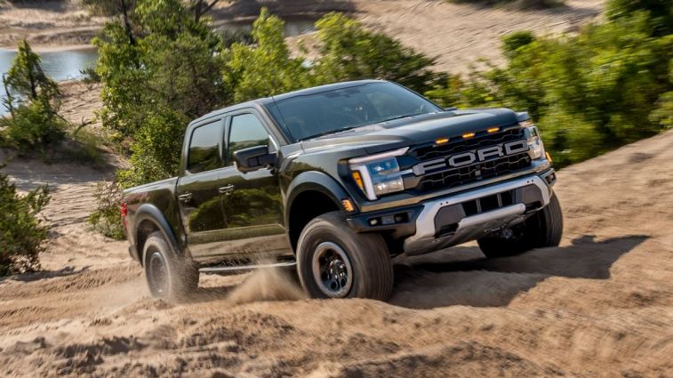2024 Ford F-150 Raptor driving up a dirt trail.