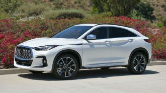 2024 Infiniti QX55 in Radiant White with shrubs in the background.