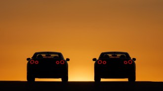 The 2024 Nissan GT-R Skyline and T-Spec Takumi Special Editions seen from the rear, driving into a sunset
