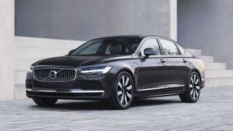 2024 Volvo S90 Recharge T8 AWD in Platinum Grey parked in front of a building.