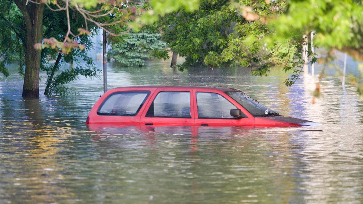 A vehicle sitting in floodwater up to its windows.
