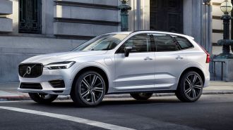 2021 Volvo XC60 Recharge Plug-In Hybrid R-Design in Crystal White Pearl driving down a city street.