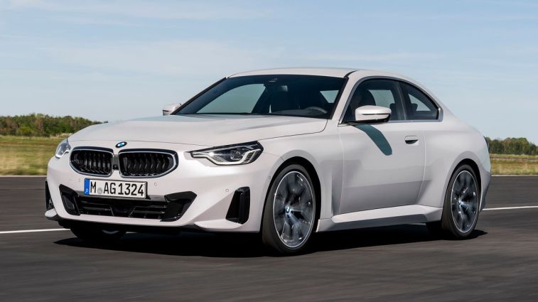 سيارة BMW الفئة الثانية كوبيه 2024 باللون الأبيض أثناء القيادة على الطريق.