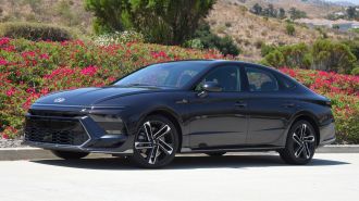 2024 Hyundai Sonata N Line in Carbon Blue with trees and bougainvillea in the background.
