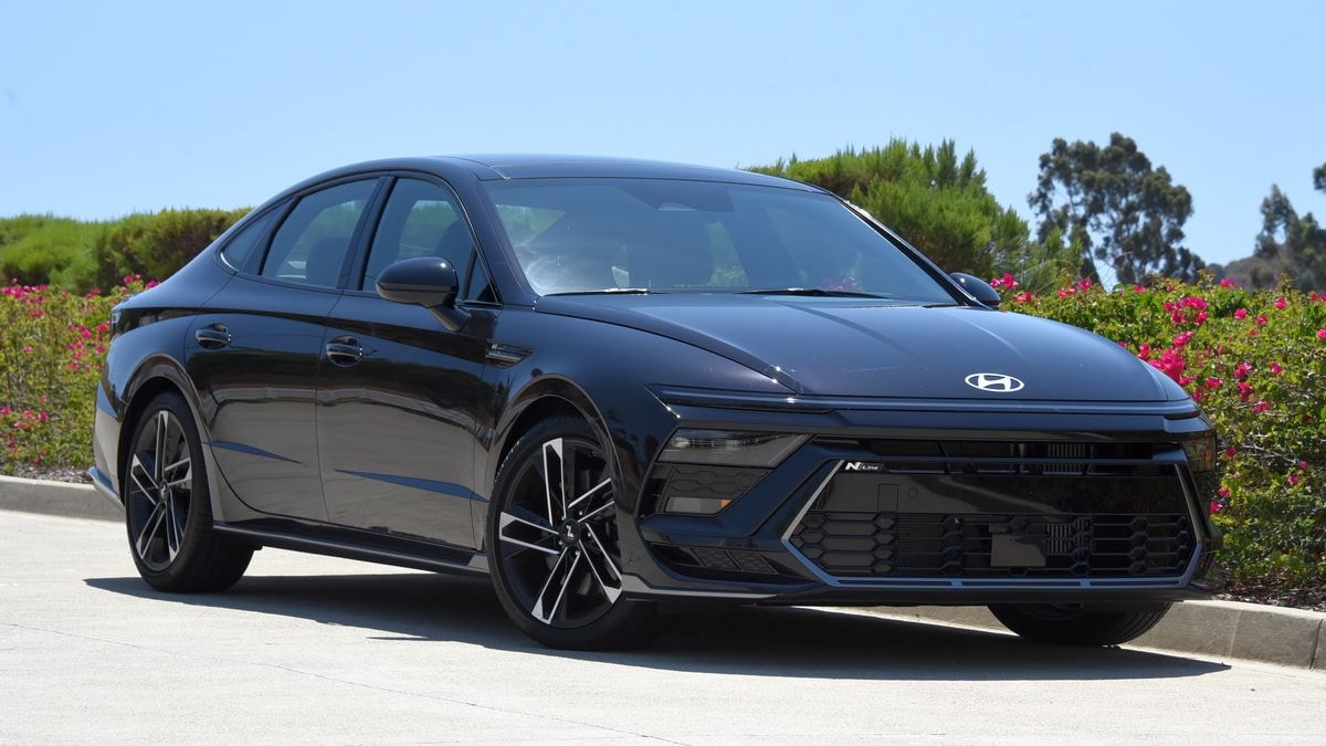2024 Hyundai Sonata N Line in Carbon Blue with trees and bougainvillea in the background.