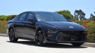 2024 Hyundai Sonata N Line in Carbon Blue with trees and bougainvillea in the background.