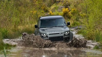 The 2025 Defender Octa seen from a front quarter angle, fording water