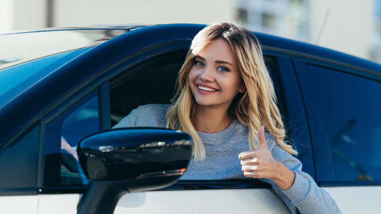 New teen driver smiling and giving thumbs up.