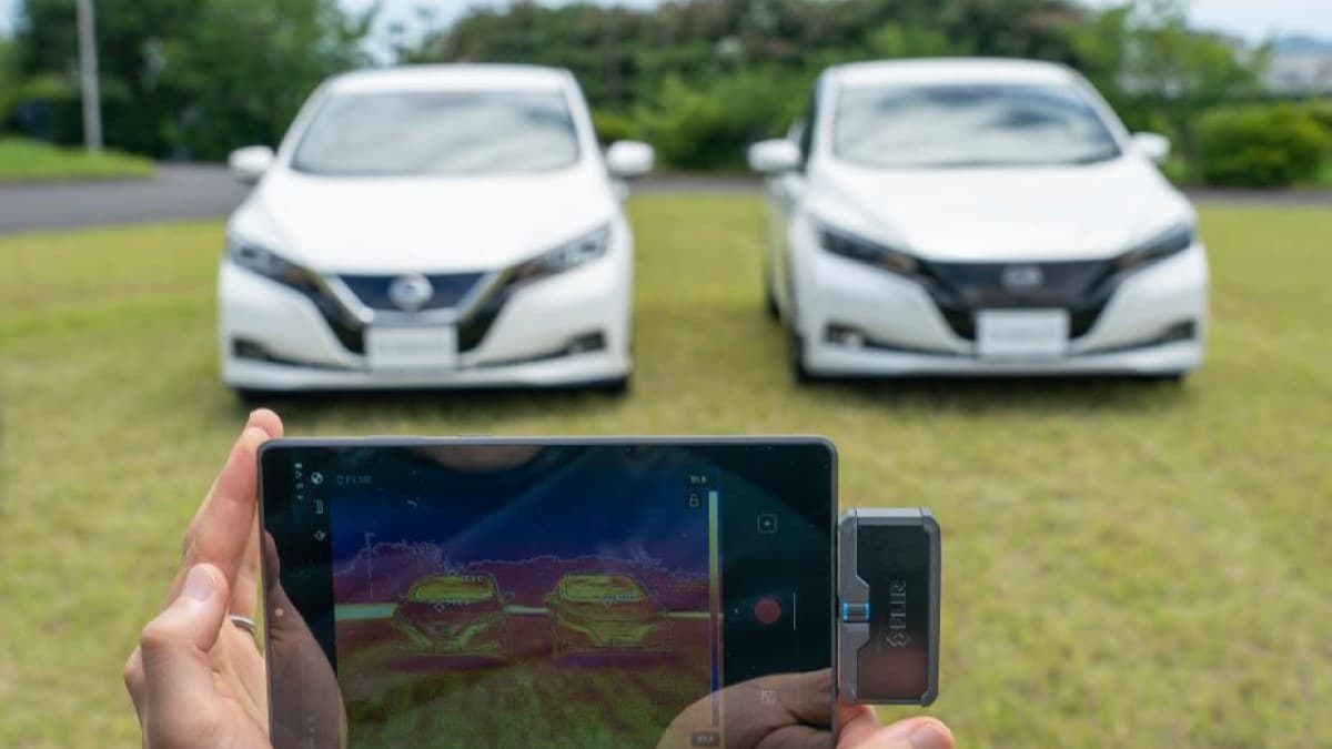 A photo showing two Nissan Leaf EVs, one cooler than the other in summer sun thanks to an experimental paint