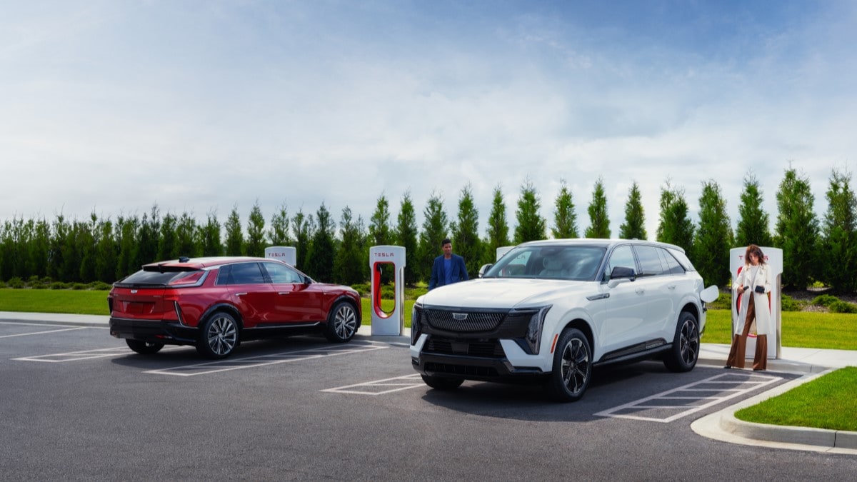 A Cadillac Escalade IQ and a Cadillac Lyriq charge at Tesla Superchargers