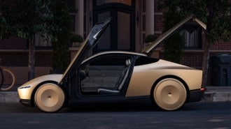 The Tesla Robotaxi seen in profile with its doors and trunk open