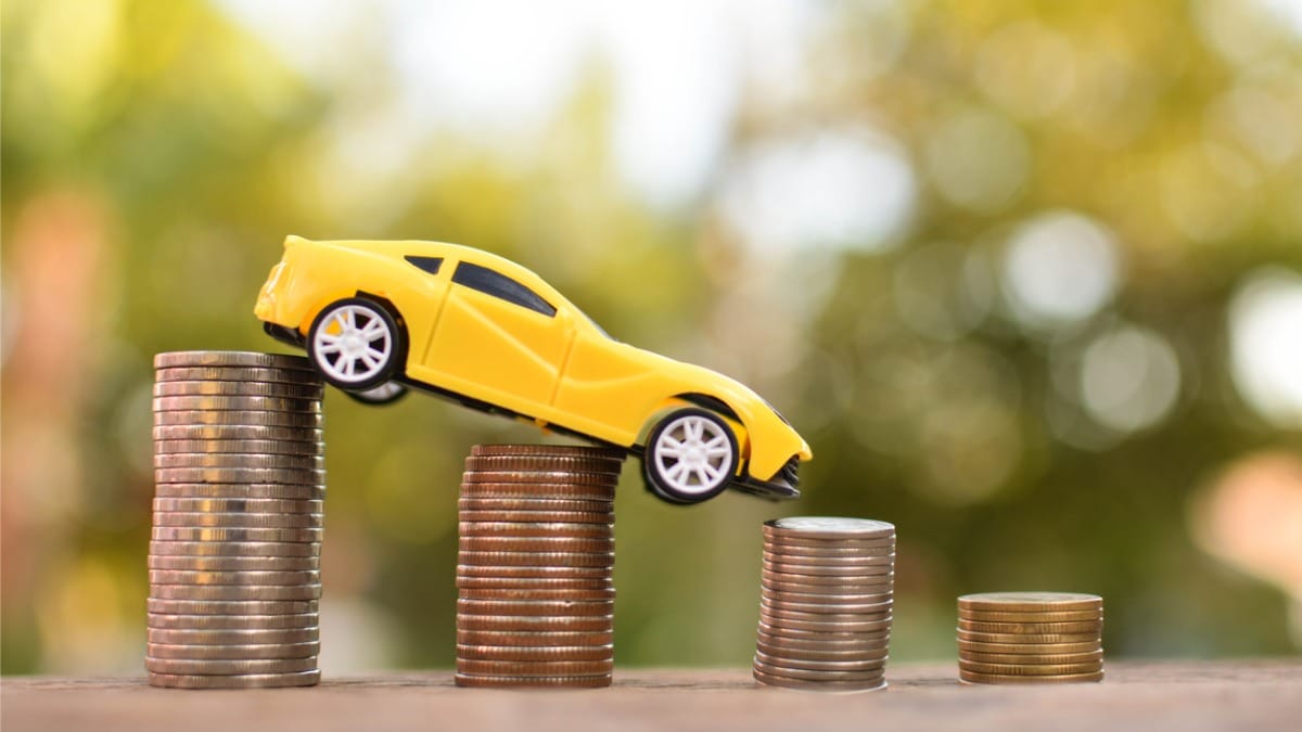Yellow toy car descending a stack of coins.