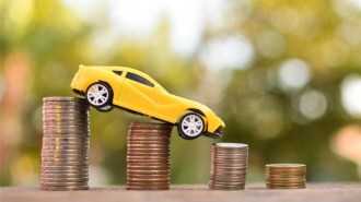 Yellow toy car descending a stack of coins.
