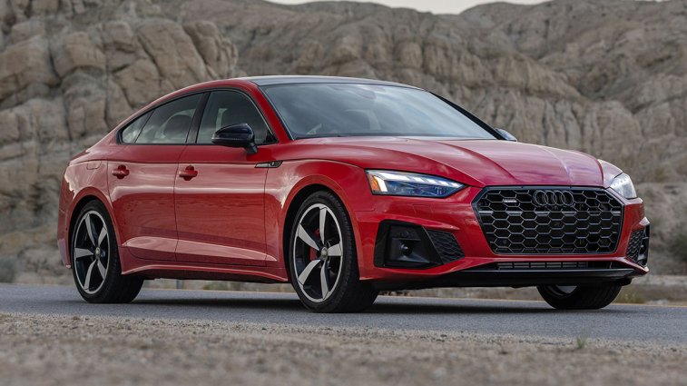 2025 Audi A5 Sportback in red, parked in the desert near cliffs.