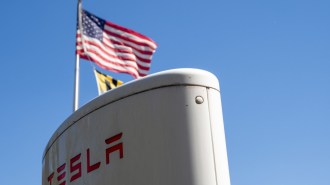 An American flag waving above a Tesla Supercharger