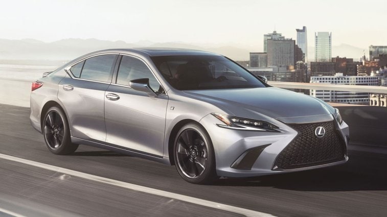The 2025 Lexus ES driving on the highway with a city in the background.