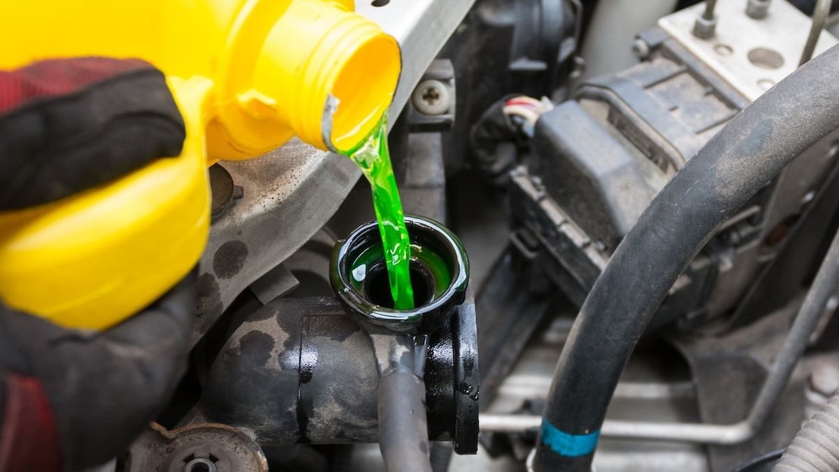 A technician pouring engine coolant.