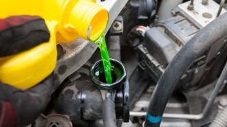 A technician pouring engine coolant.