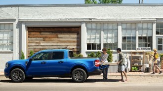 People loading items into Ford Maverick bed.