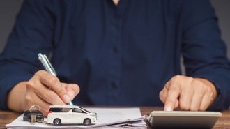Person signing paperwork for buying a car.