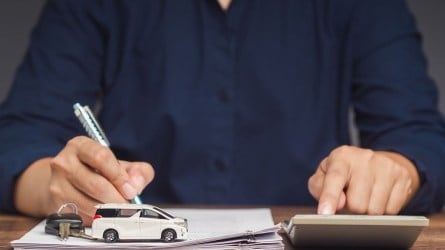 Person signing paperwork for buying a car.