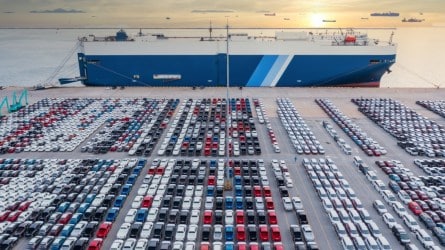 cars parked in port near the ship that delivered them